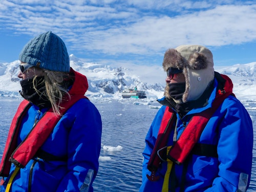 2 people wearing blue jackets sitting looking out at the dramatic landscapes 