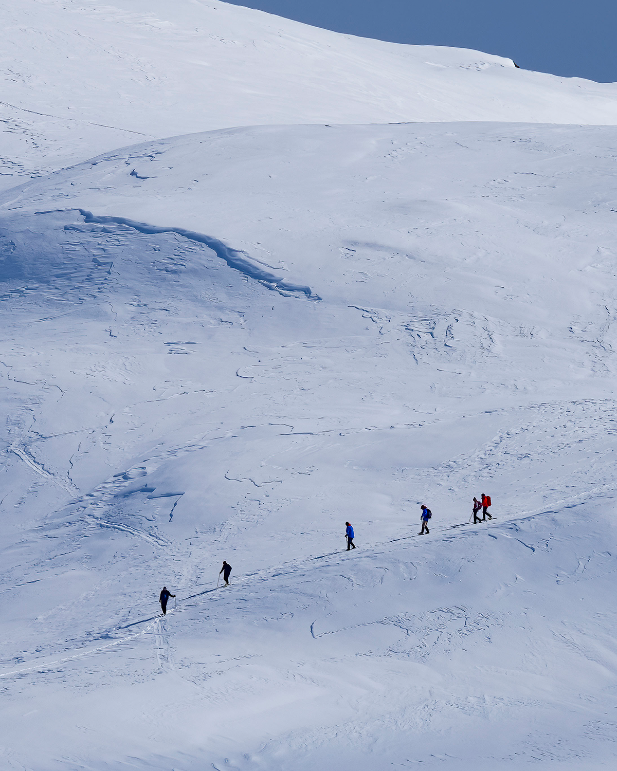 4 people hiking up a snowy mountain in the distance