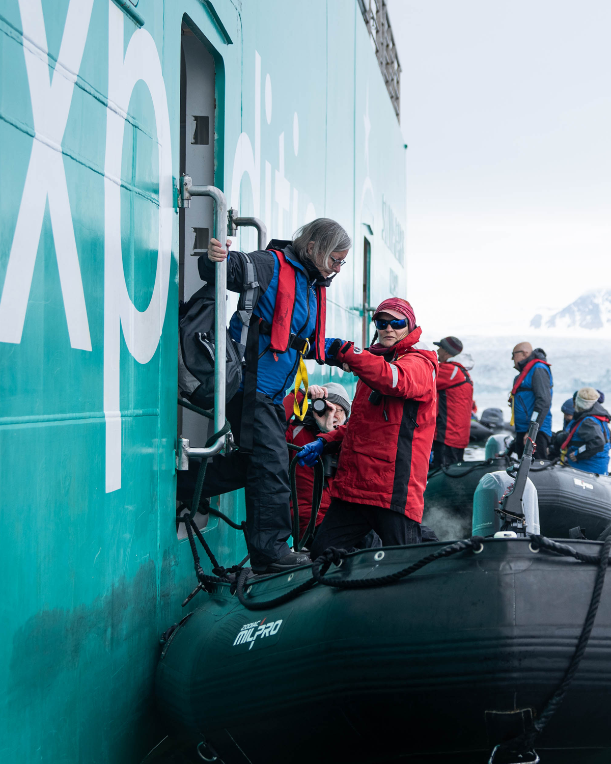 A passenger being helped onto a zodiac by Expedition Team.